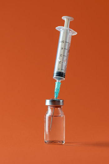 Close-up of water bottle against orange background