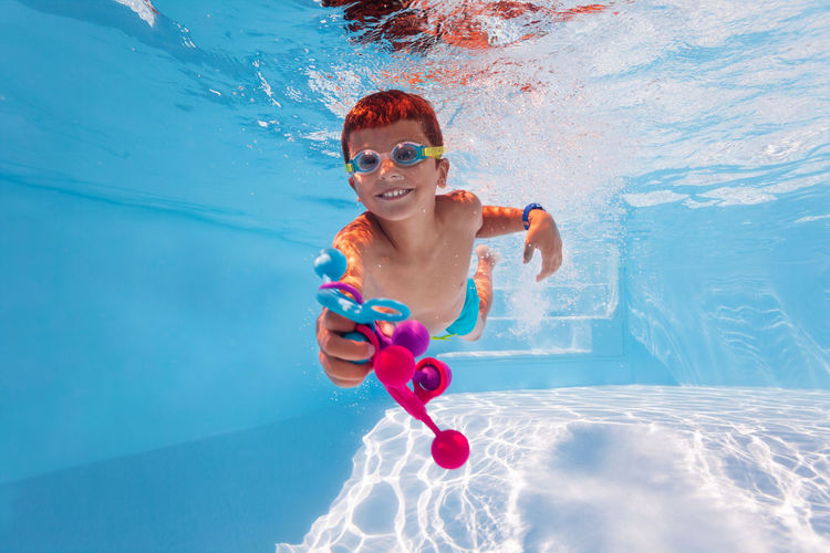 Happy boy playing with toy in swimming pool
