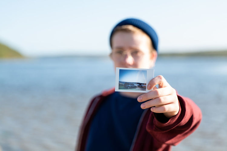 Portrait of man holding smart phone against sea