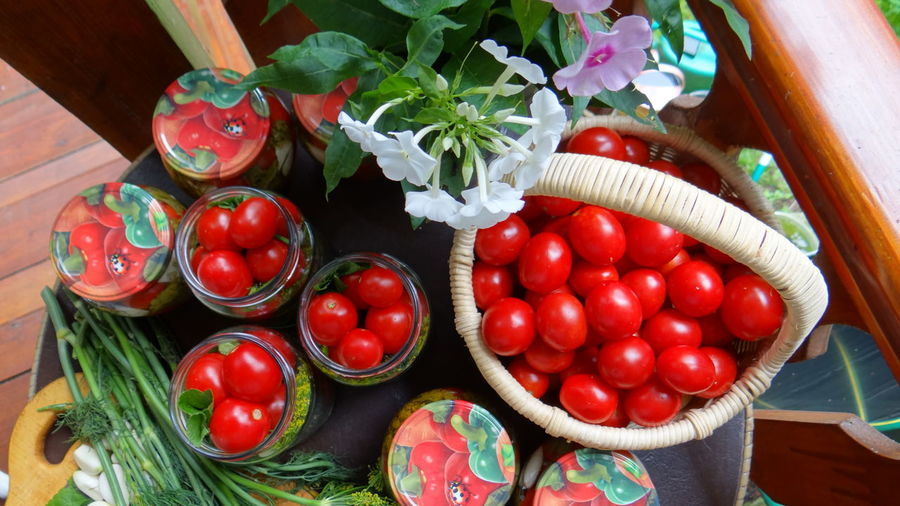 Close-up of tomatoes in glass jars and basket on table