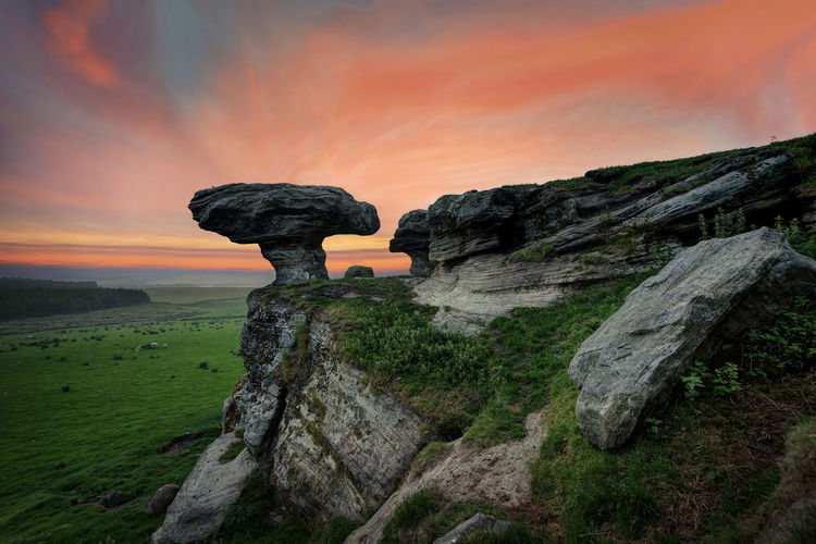 Rock formation on land against sky during sunset
