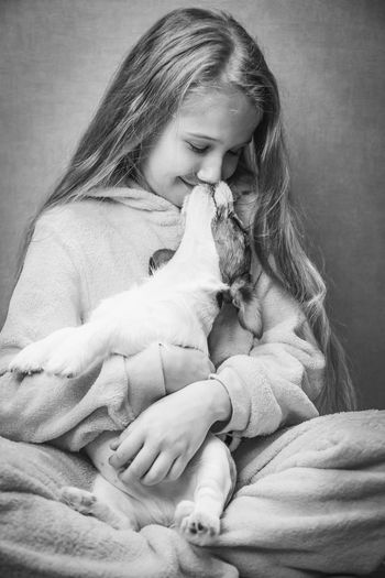 Beautiful girl in sits cross-legged on the floor and holds in arms a cute puppy of jack russell 