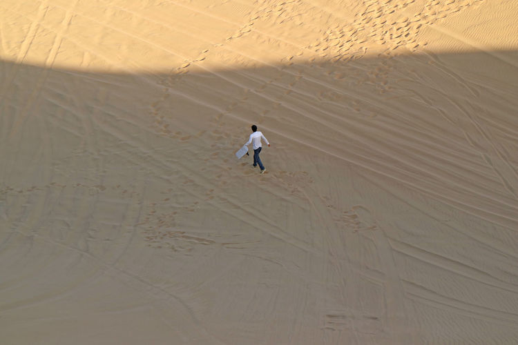 Aerial view of man walking on sand dune