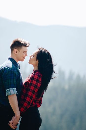 Side view of young couple standing face to face in forest