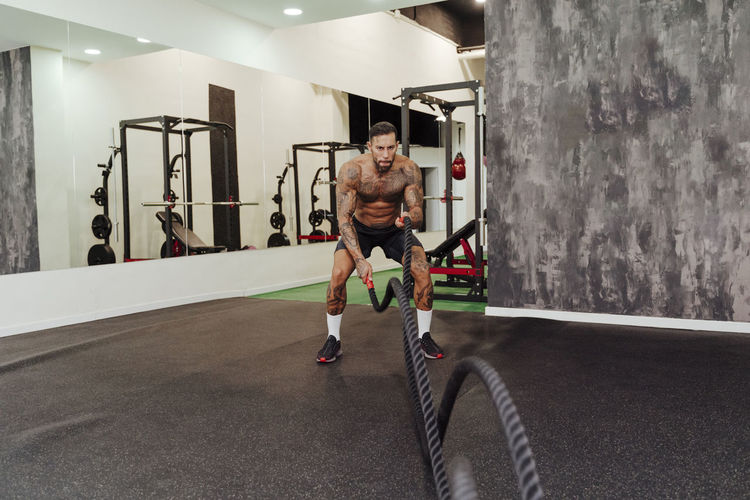 Male athlete exercising with rope in gym