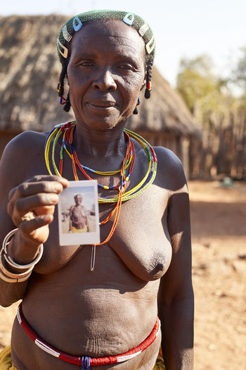 Mudimba tribe woman showing a picture of herself, canhimei, angola.