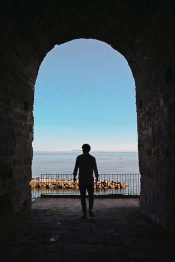 Rear view of silhouette man standing by sea in sorrento, italy
