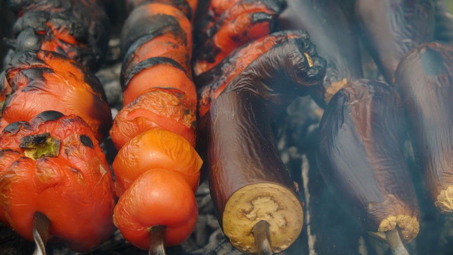 Close-up of vegetables on skewers roasting on a charcoal grill. peppers, tomatoes and eggplants