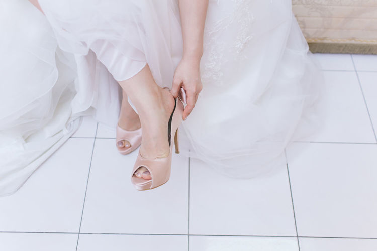 Low section of bride wearing sandal on floor