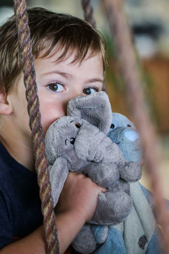 Portrait of cute boy with stuffed toys sitting on swing
