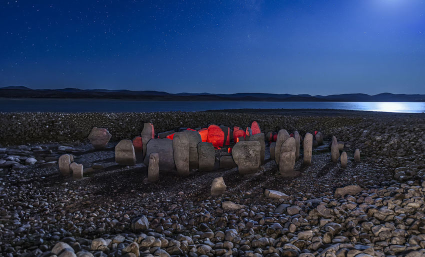 Stones on beach against sky at night