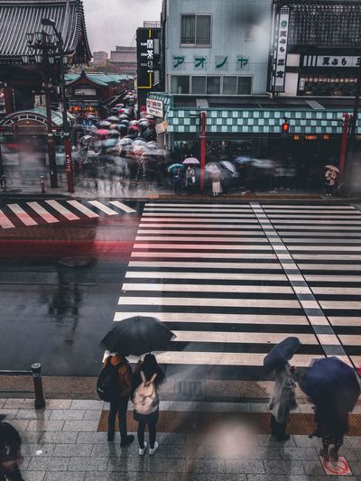 People crossing road in city during rainy season