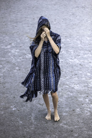 Full length of woman covering face while standing 