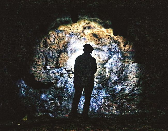 Rear view of man standing in cave