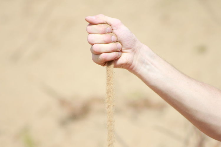 Close-up of hand holding sand at beach