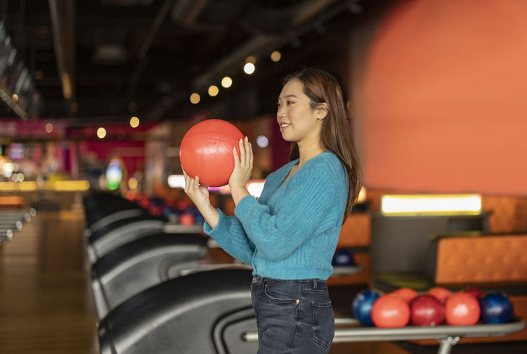 Young woman holding bowling ball at alley