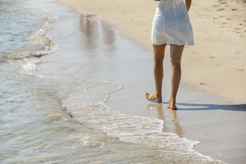 Low section of woman walking at beach