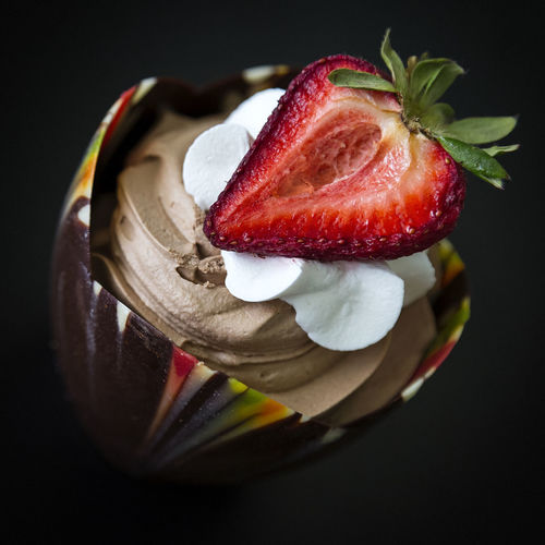 Close-up of sliced strawberry with whipped cream in bowl on table