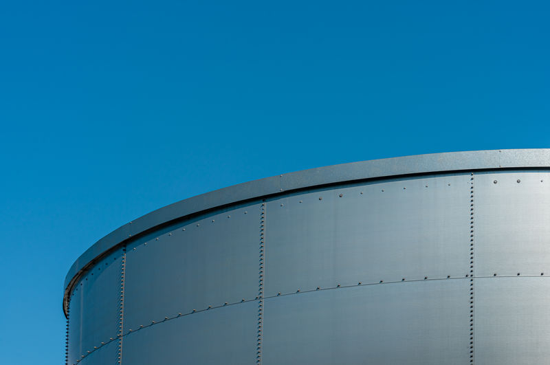 Low angle view of tank against clear blue sky