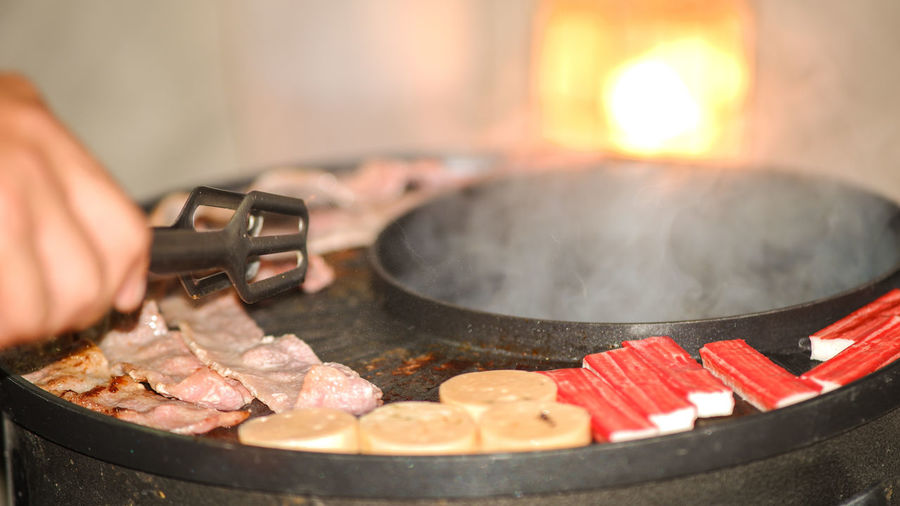 Cropped image of person preparing food on barbecue grill