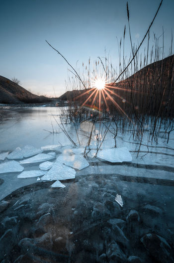 Scenic view of frozen lake against sky during sunset