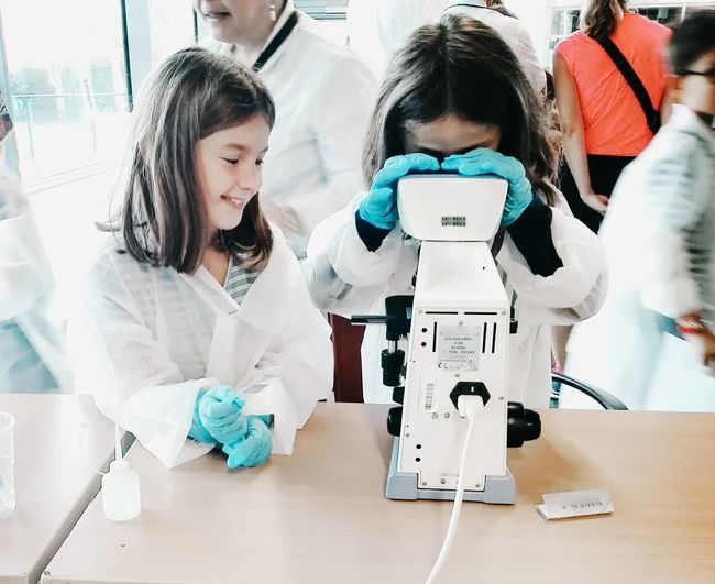 Girls learning science and using a professional microscope