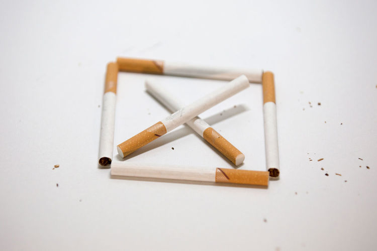 High angle view of cigarette on table against white background