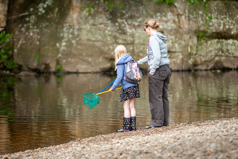 Rear view of mother and son standing in lake