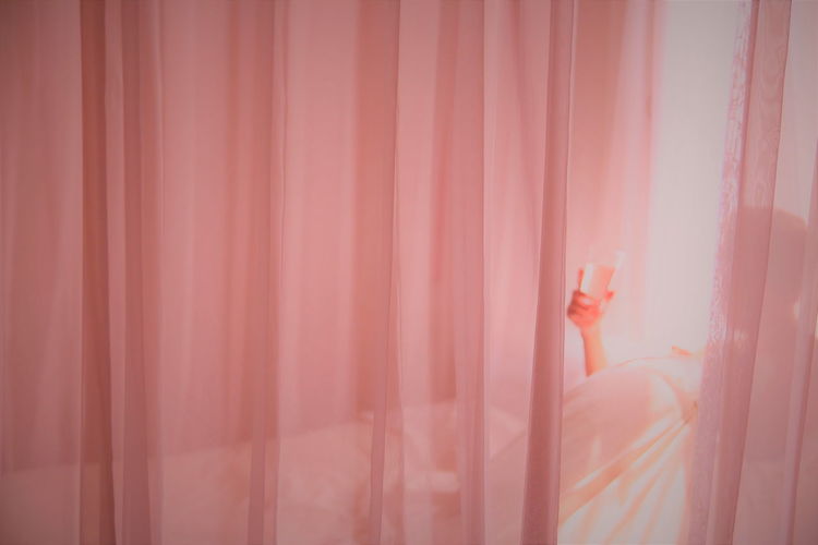 Person relaxing behind pink curtain
