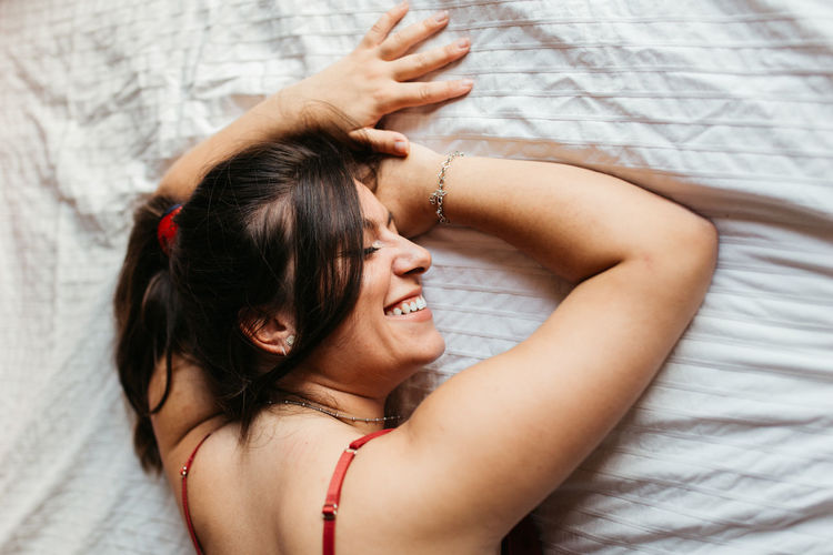 Directly above shot of smiling woman lying on bed at home