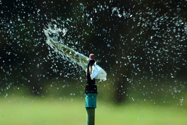 Close-up of sprinkler against blurred lawn