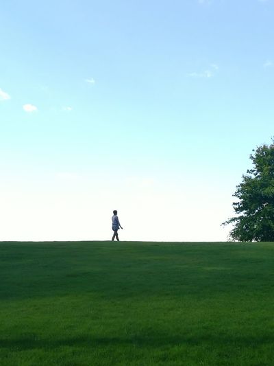 Woman walking on grassy field against sky