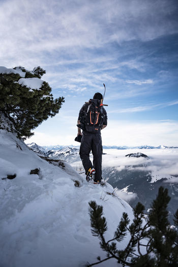 Man standing on snowcapped mountain against sky