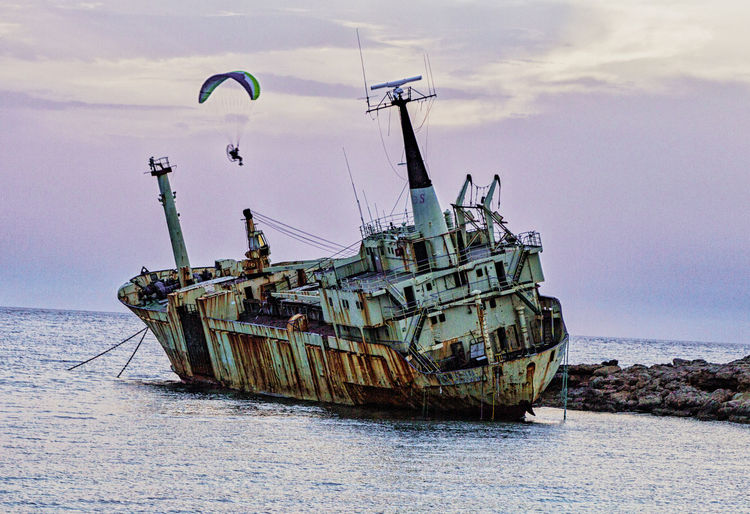 Abandoned fishing boat in sea against sky