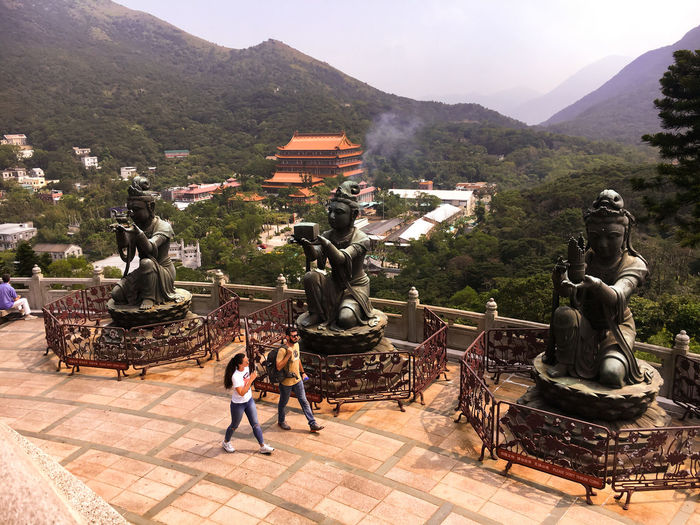 Statue of buddha and buildings against mountain