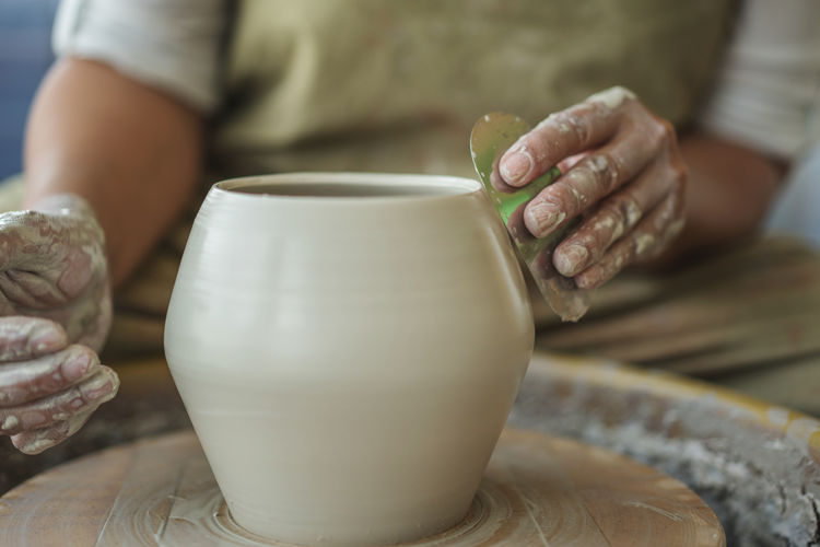 Midsection of woman making pottery in workshop