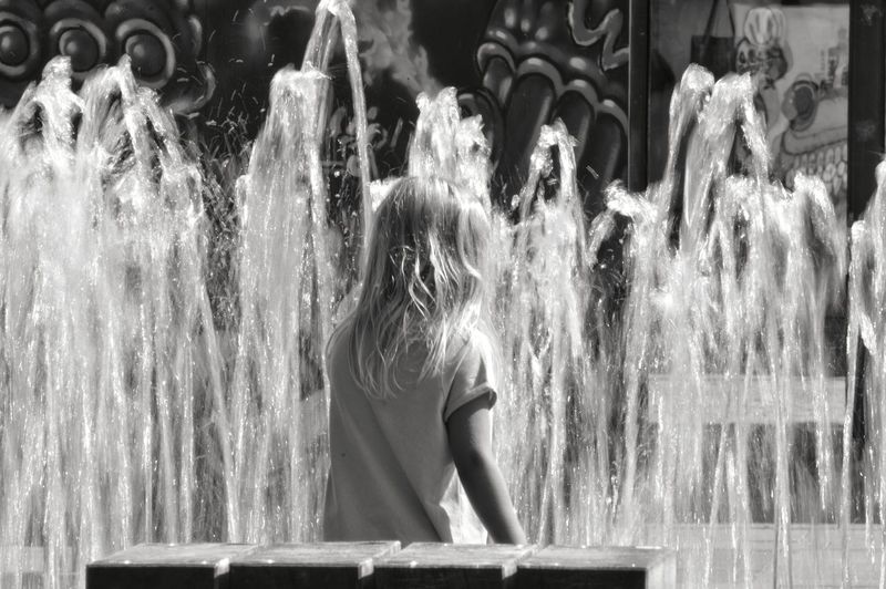 Rear view of girl standing against fountain