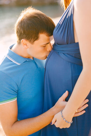 Man kissing woman stomach outdoors