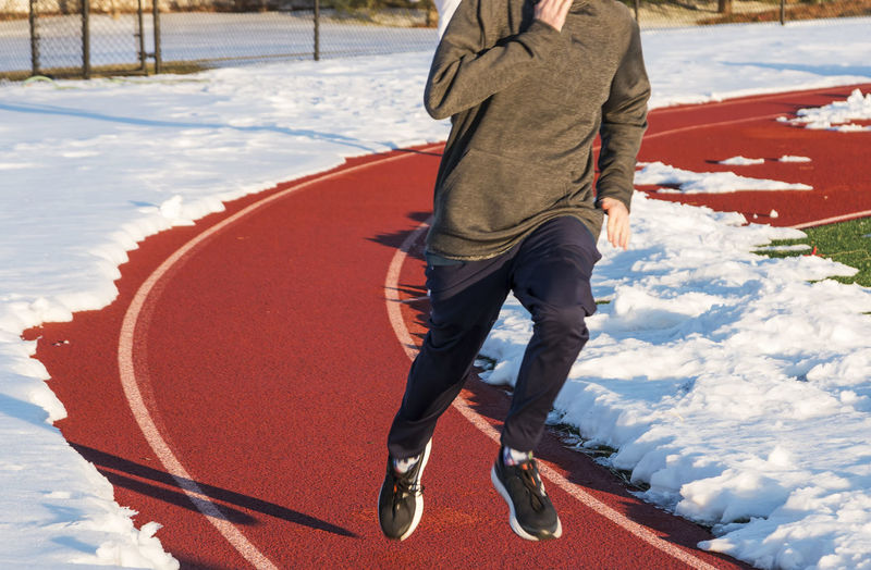 Low section of man running on sports track during winter