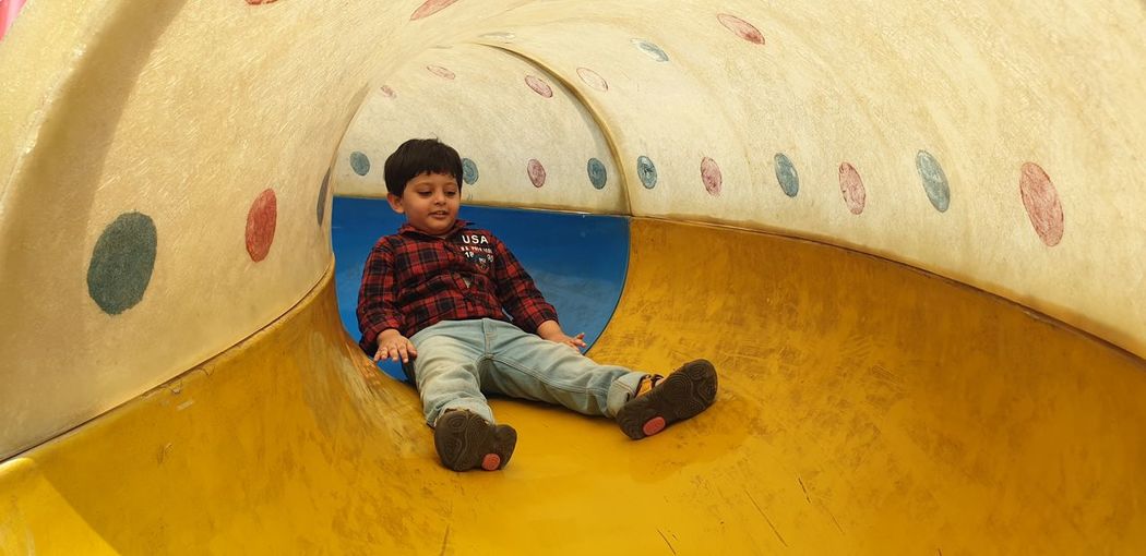 Boy sliding inside the tunnel shaped slider