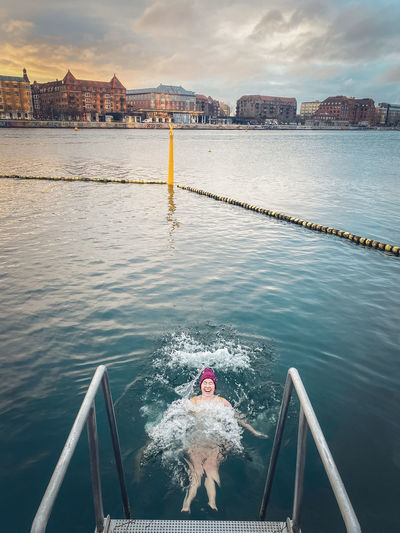 Laughing winter bather making waves in still water copenhagen, denmark