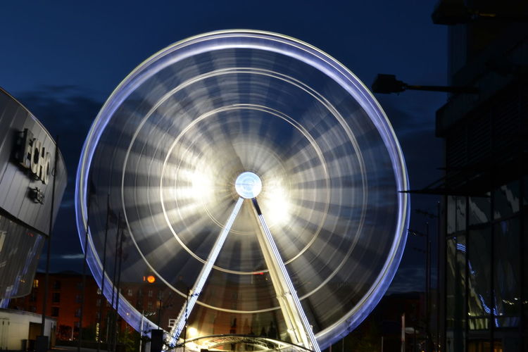 Illuminated blurred ferris wheel against the sky