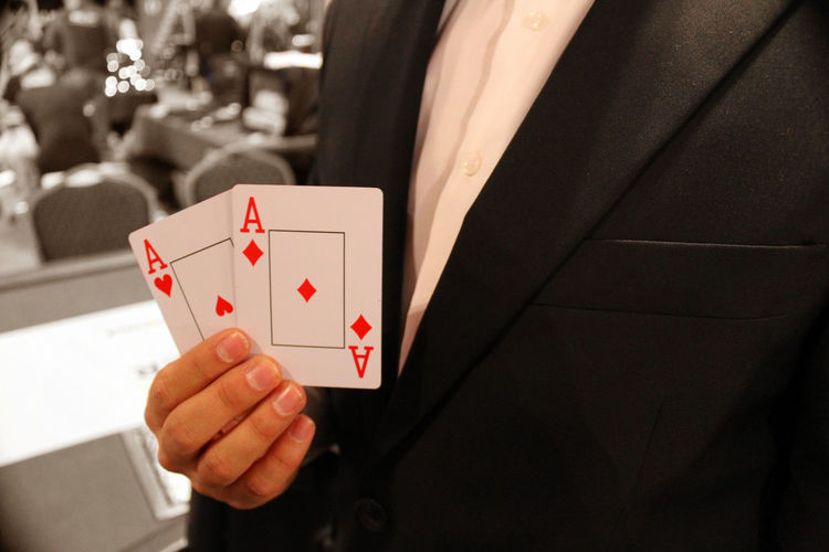 Midsection of businessman holding playing cards
