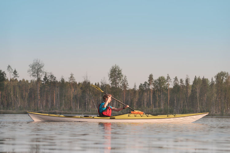 A man is swimming in a kayak. side view
