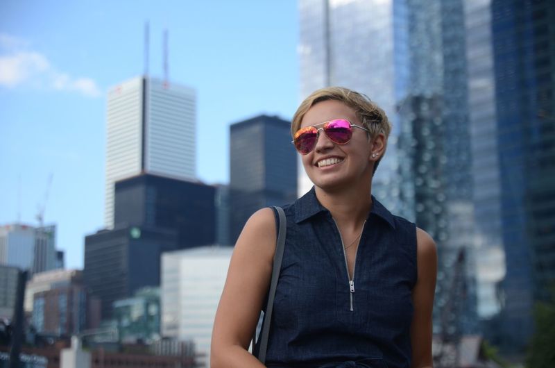 Happy young woman wearing sunglasses in city