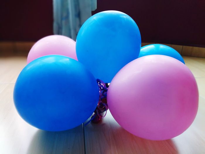 Close-up of blue and pink balloons on hardwood floor