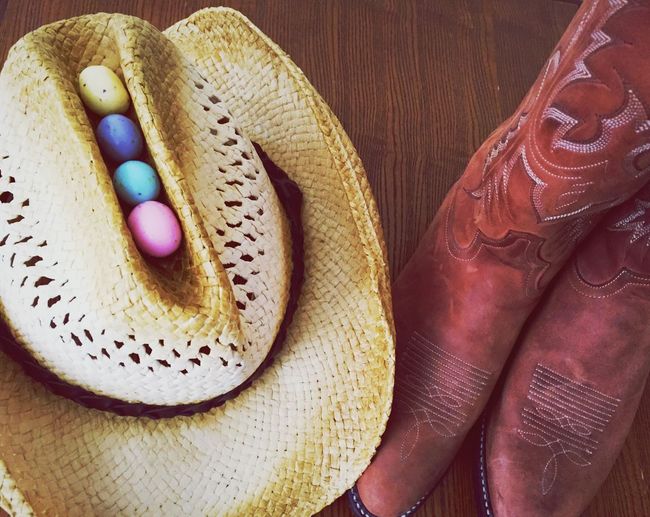High angle view of cowboy hat with easter eggs by boots on table