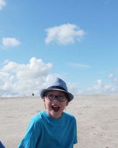 Portrait of boy wearing sunglasses on beach against sky