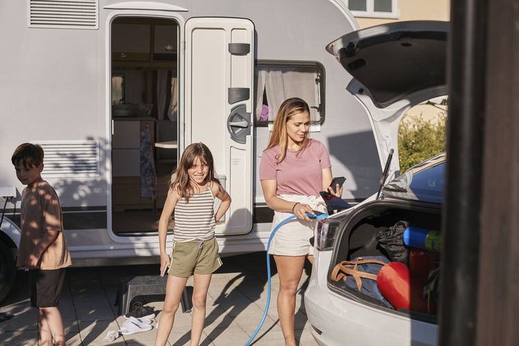 Mother with children standing near car