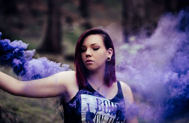 Portrait of beautiful young woman standing against purple outdoors